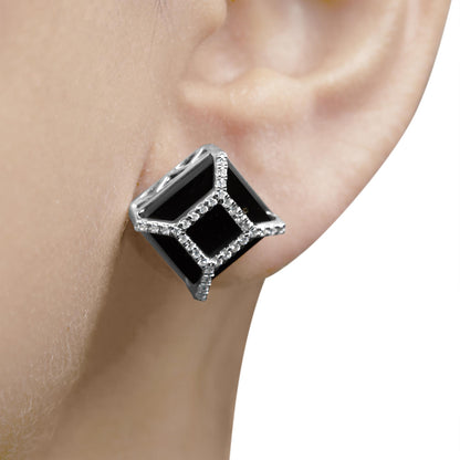Close-up side view of a white metal earring on a model's ear, featuring black cushion-shaped gemstones surrounded by round white gemstones in pave setting.