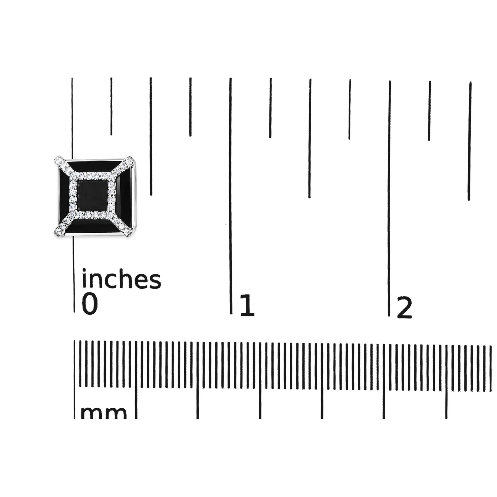 Close-up of a white metal square-shaped earring with a black cushion-shaped gemstone in the center and surrounded by small round white gemstones, placed on a ruler for size reference.