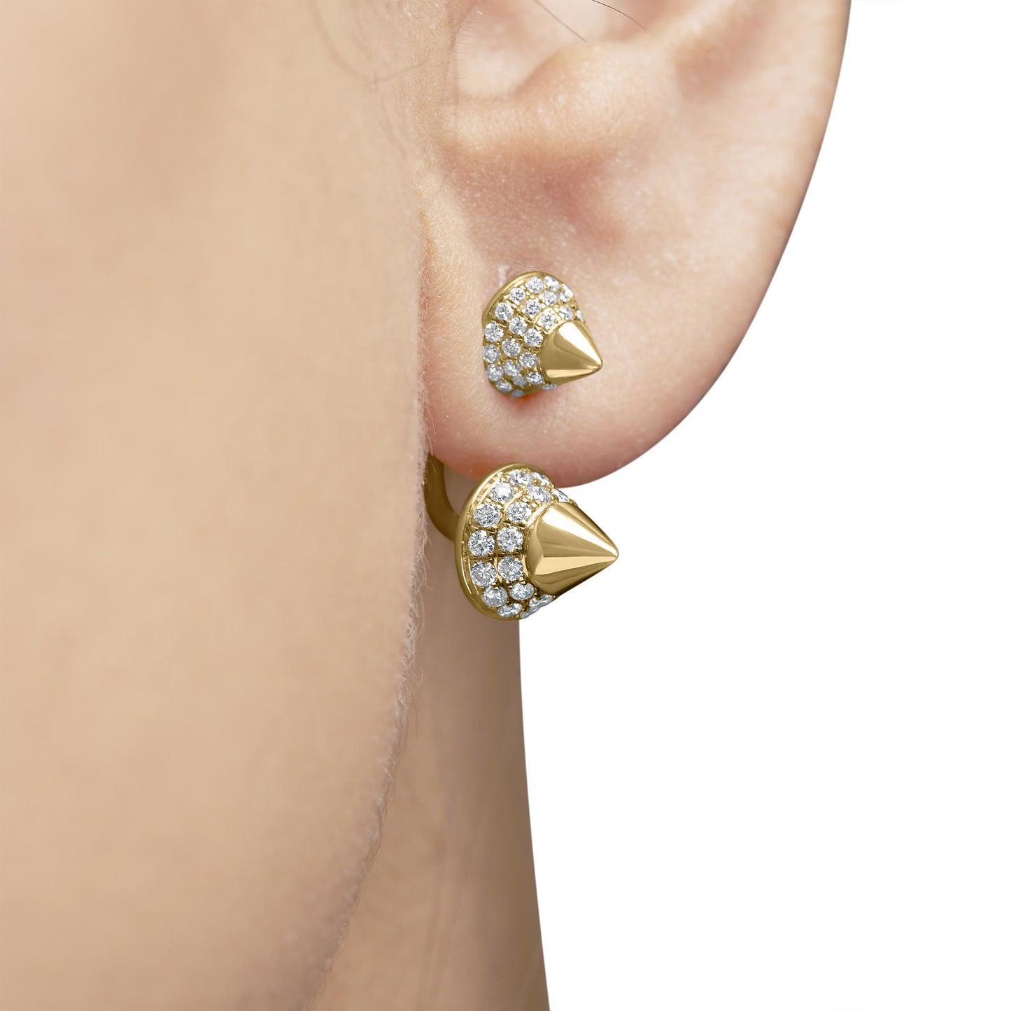 Close-up side view of rose metal earrings on a model's ear, featuring round white gemstones in a pave setting with a pointed tip design.