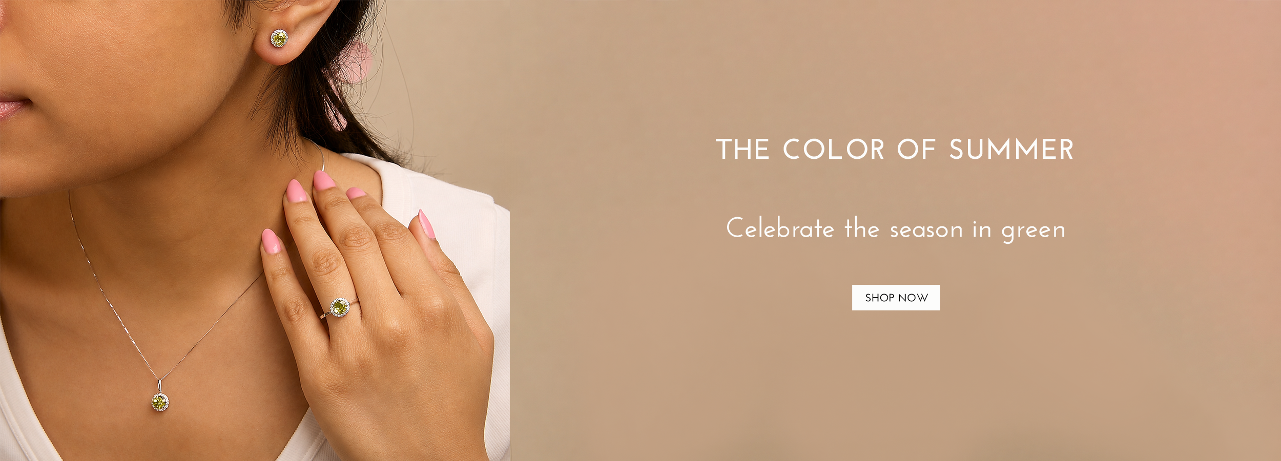 A close-up lifestyle shot of a woman wearing a delicate gold necklace with a green pendant and a matching green ring on her finger, set against a warm beige background with promotional text.