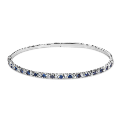 Close-up front angle of a white bracelet featuring alternating round blue and white gemstones in prong settings, displayed on a white background.