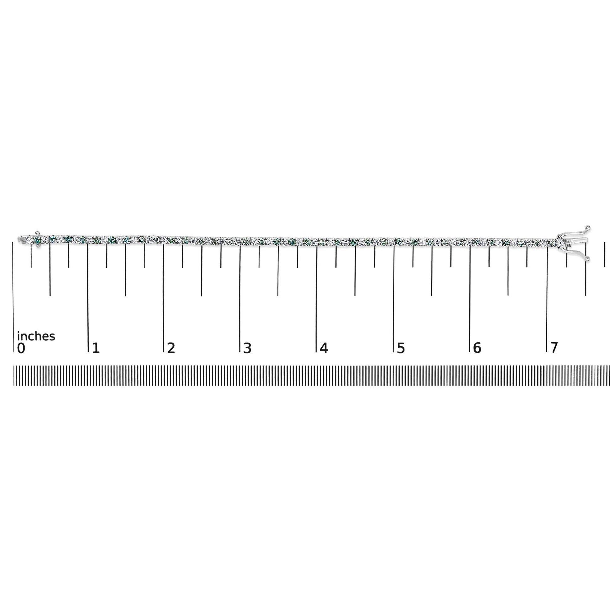 White metal bracelet with alternating white and blue round gemstones in four-prong settings, laid flat on a ruler for size reference, shown from a top-down angle.