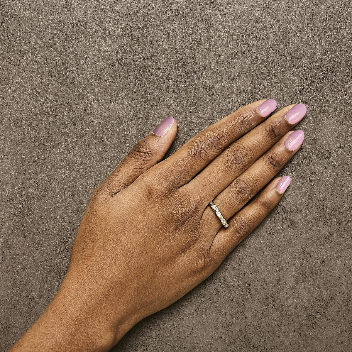 Yellow ring with multiple pear-shaped white gemstones in 3-prong settings, shown worn on a model's hand, top-down angle.