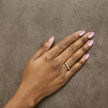 Yellow ring with multiple pear-shaped white gemstones in 3-prong settings, shown worn on a model's hand, top-down angle.
