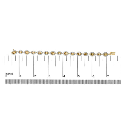 Yellow metal bracelet with alternating oval yellow gemstones surrounded by small white gemstones in a pave setting, shown on a flat surface with a measuring scale, front view.