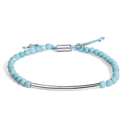 Bracelet with light blue faceted gemstones and a smooth curved white metal bar, shown flat from an overhead angle on a white background.