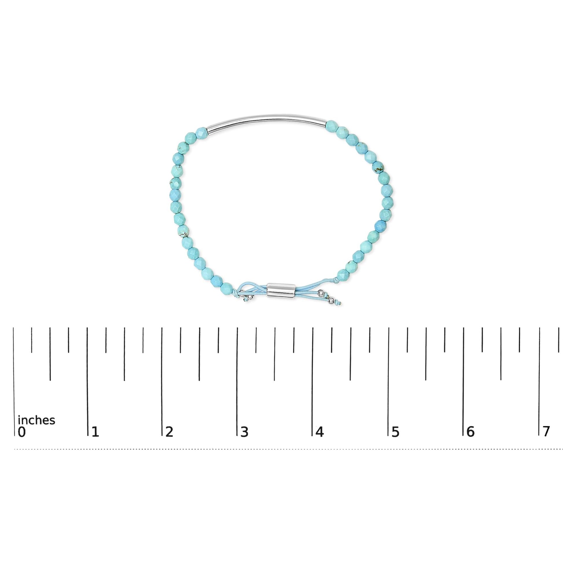 White metal bracelet with faceted blue beads and adjustable cord shown on a scale, top-down angle.