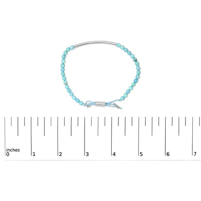 White metal bracelet with faceted blue beads and adjustable cord shown on a scale, top-down angle.