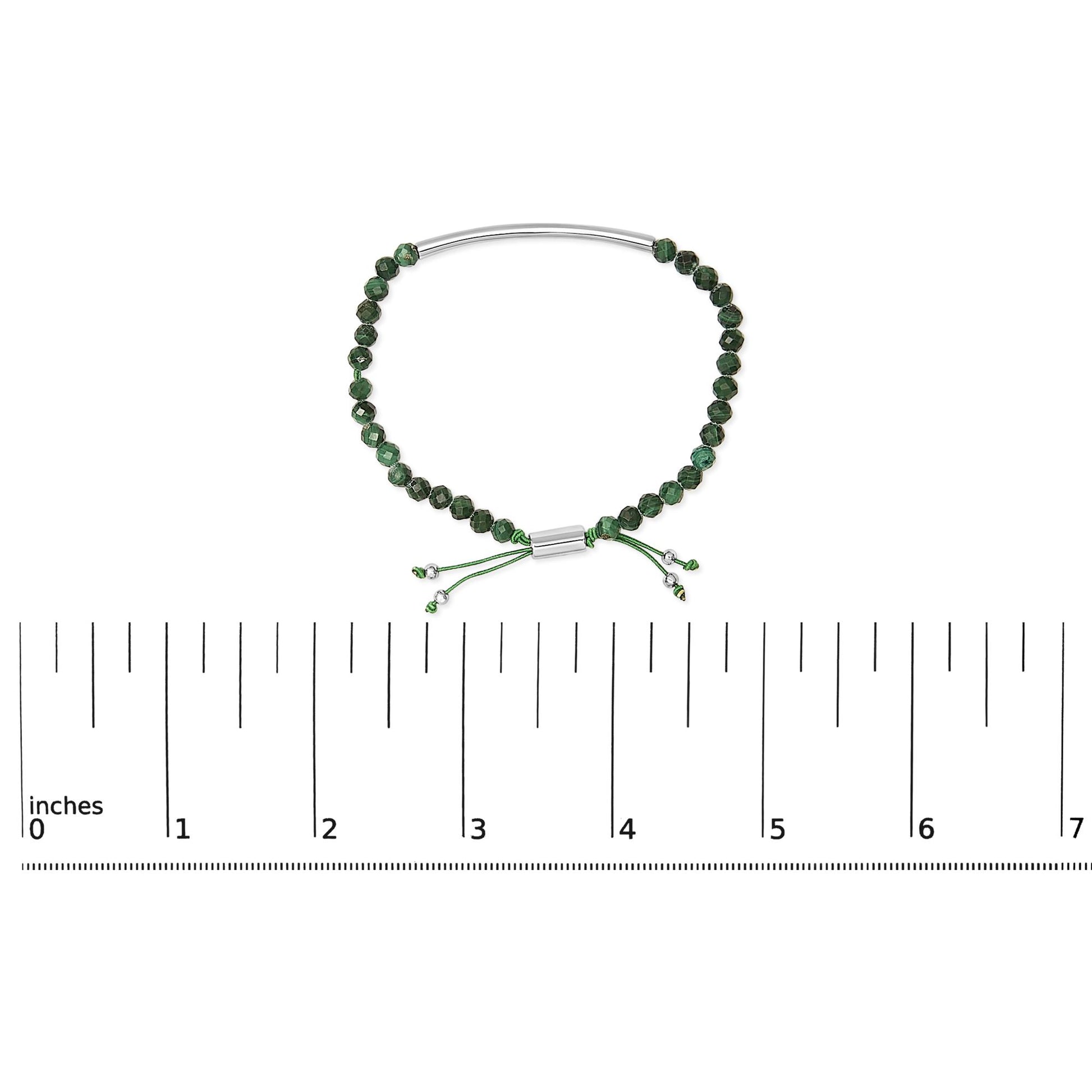 White metal bracelet with green beads and adjustable cord shown on a ruler scale, top-down view.