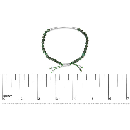 White metal bracelet with green beads and adjustable cord shown on a ruler scale, top-down view.