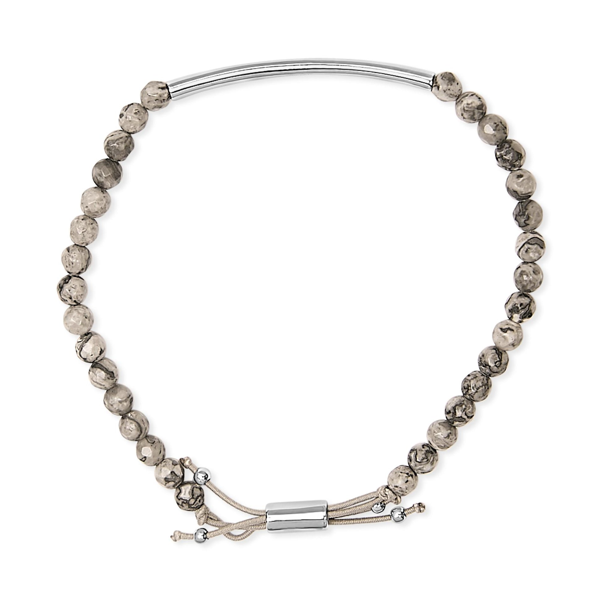Top-down view of a white metal bracelet featuring patterned round beads and an adjustable cord with metal ends.