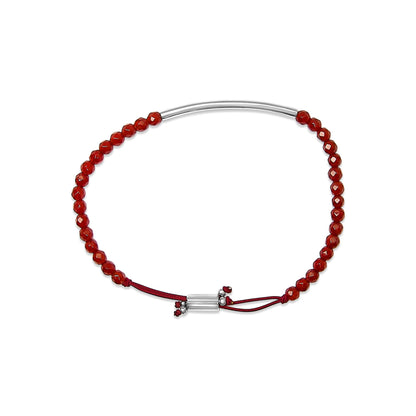 Top-down view of a white metal bracelet with faceted red gemstones strung along half the length and a red adjustable cord with a white metal sliding clasp and small red gemstone accents.