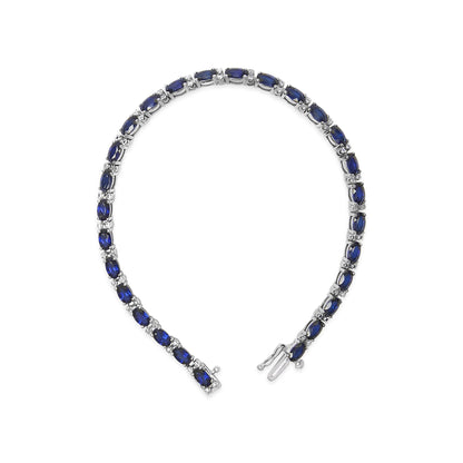 White metal bracelet shown on a white background, composed of alternating oval blue gemstones and small round white gemstones in prong settings, displayed from an overhead angle.