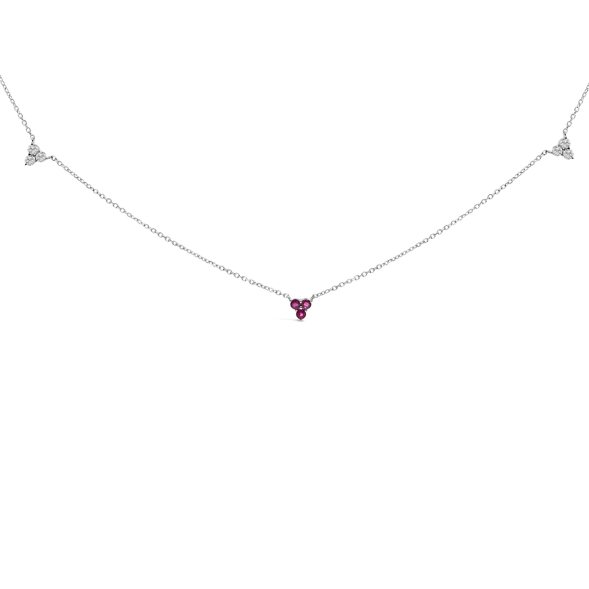 Front view of a white metal necklace with three red round gemstones in the center and two clusters of three white round gemstones along the chain, all in prong settings.