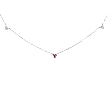 Front view of a white metal necklace with three red round gemstones in the center and two clusters of three white round gemstones along the chain, all in prong settings.