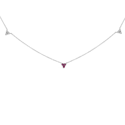 Front view of a white metal necklace with three red round gemstones in the center and two clusters of three white round gemstones along the chain, all in prong settings.