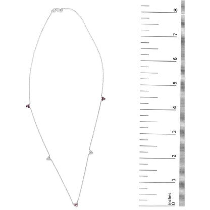 White metal necklace shown on a scale, featuring small triangular clusters of red and white round gemstones in prong settings spaced along a delicate chain. The image is a top-down view.