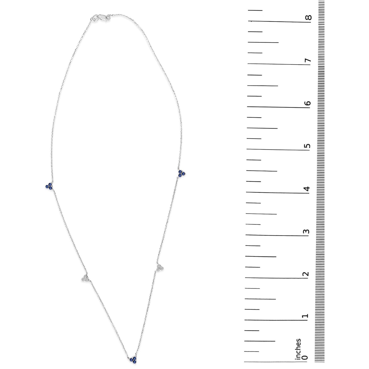White necklace with small clusters of round white gemstones and blue gemstones in prong settings, shown on a scale from top view.