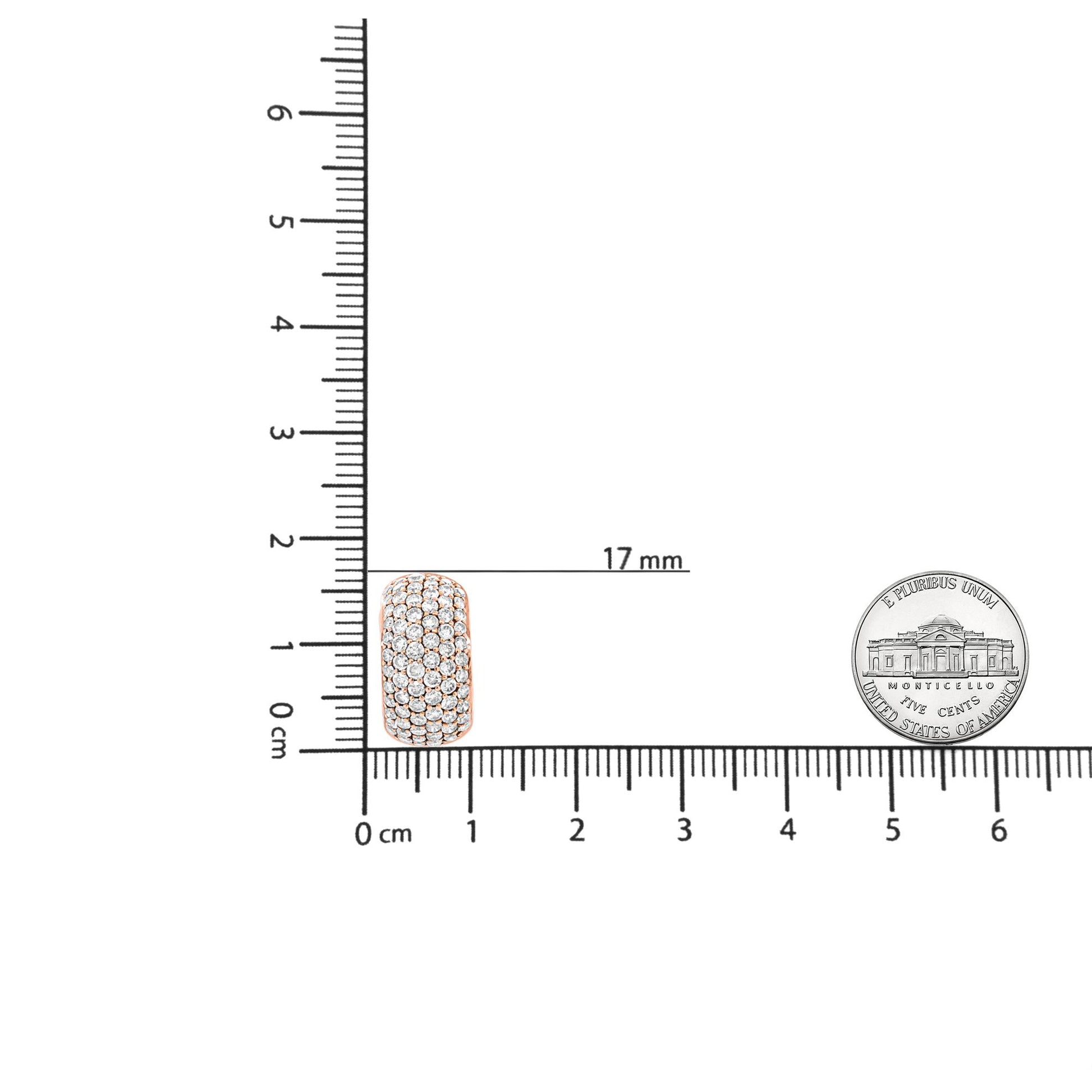 Close-up front view of a rose metal earring with multiple round white gemstones in prong settings, placed on a ruler for size reference.