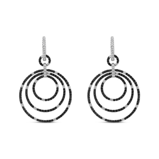 Front view of white metal earrings with three concentric hoop shapes adorned with alternating black and white round gemstones in prong settings.