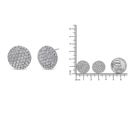 Pair of round white metal stud earrings encrusted with multiple small round white gemstones, shown from a front angle on the left and placed next to a ruler and coin for size reference on the right.