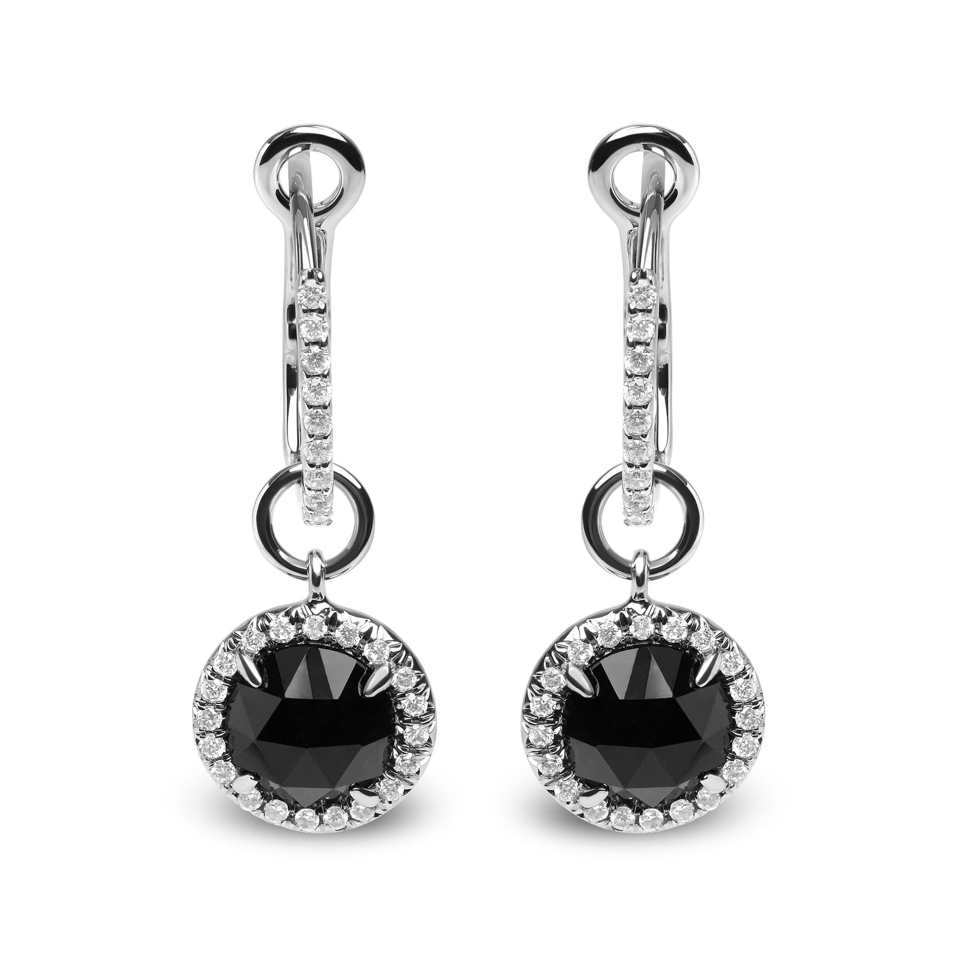 Front-facing shot of white metal drop earrings with a round black gemstone surrounded by small white gemstones, hanging from a white metal hoop also accented with white gemstones.