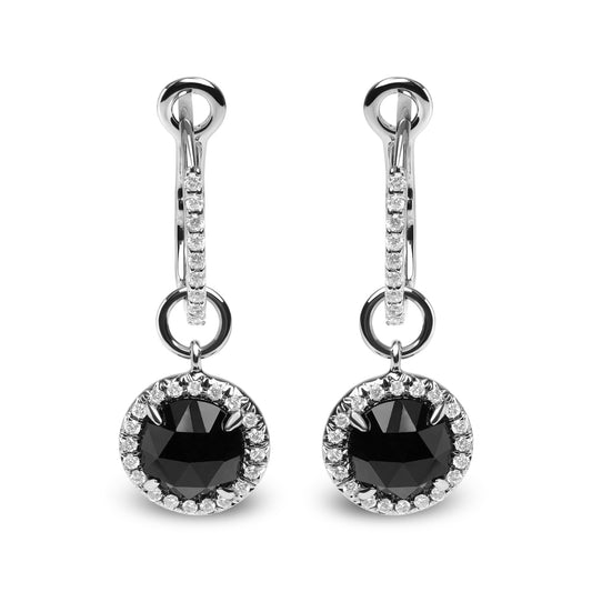 Front-facing shot of white metal drop earrings with a round black gemstone surrounded by small white gemstones, hanging from a white metal hoop also accented with white gemstones.