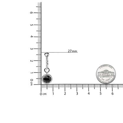 Single white metal earring with a round black gemstone surrounded by small white gemstones, shown on a ruler for size reference, viewed from the front.