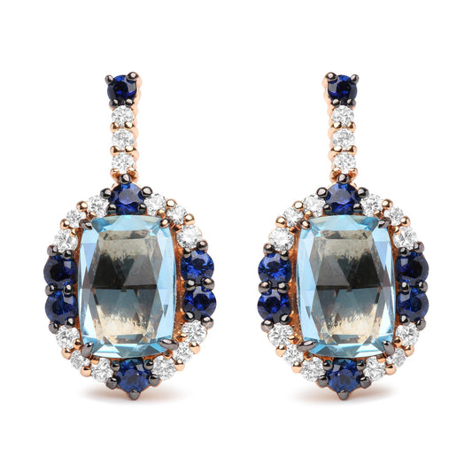 Pair of drop earrings photographed from the front, featuring large cushion-shaped blue gemstones surrounded by round blue and white gemstones, set in white and rose-colored metal.