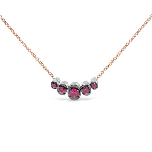 Front view of a rose metal necklace featuring a curved row of round red gemstones in prong settings, accented with small round white gemstones in pave settings.