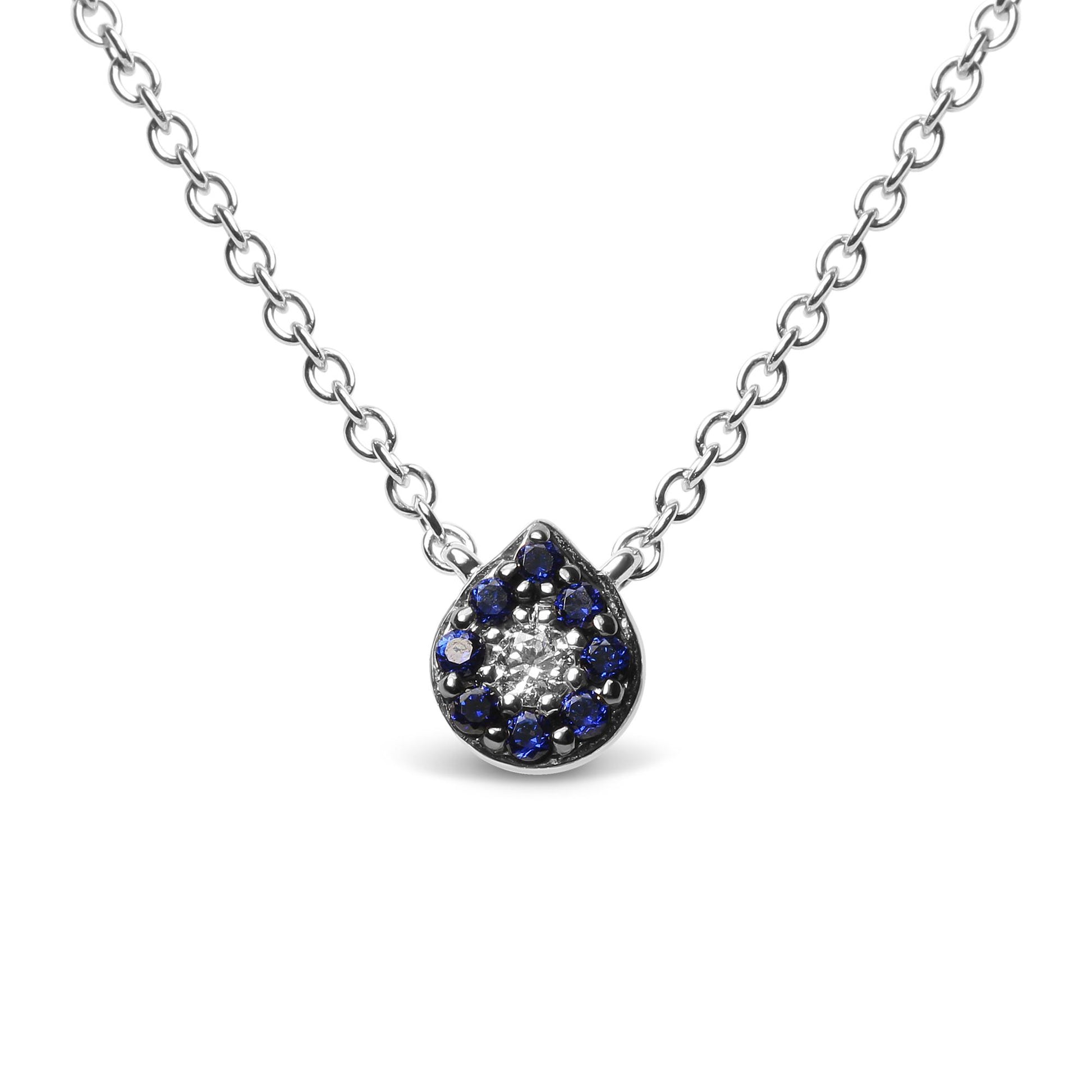 Close-up front view of a white metal necklace with a teardrop-shaped pendant featuring a cluster of round blue gemstones surrounding a single round white gemstone, all in prong settings.