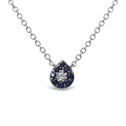 Close-up front view of a white metal necklace with a teardrop-shaped pendant featuring a cluster of round blue gemstones surrounding a single round white gemstone, all in prong settings.