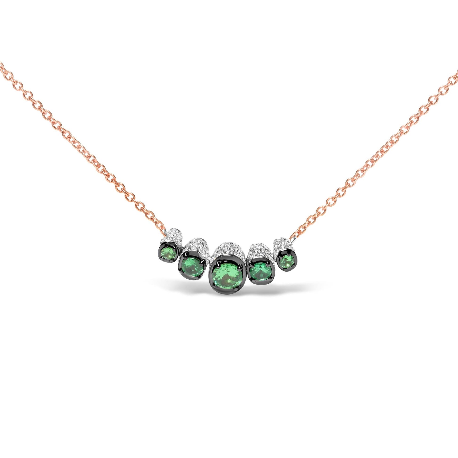 Front-facing shot of a rose metal necklace with a curved bar pendant featuring five round green gemstones surrounded by small white gemstones.