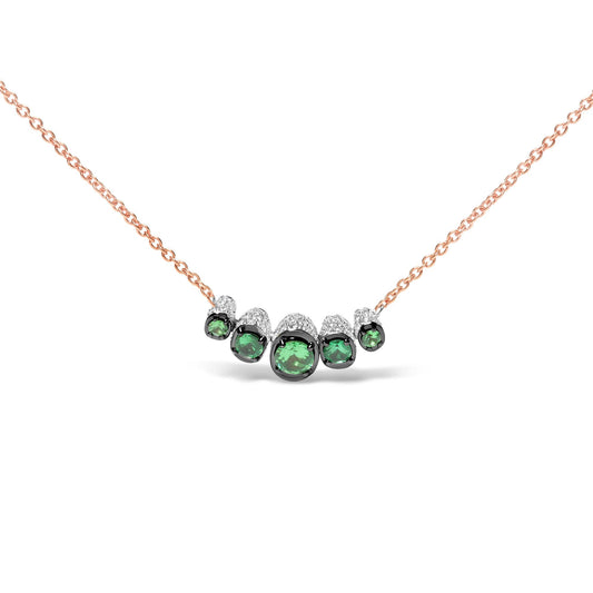 Front-facing shot of a rose metal necklace with a curved bar pendant featuring five round green gemstones surrounded by small white gemstones.