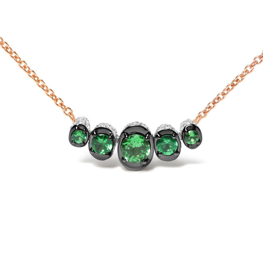 Front view of a rose metal necklace with round green gemstones in black prong settings and small white gemstones surrounding them.