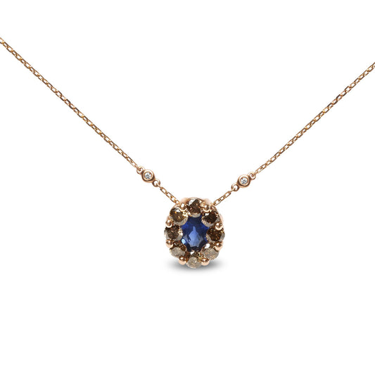 Front view of a rose-colored necklace with a central oval blue gemstone surrounded by multiple prong set round brown gemstones, two bezel set round white gemstones on the chain near the pendant.