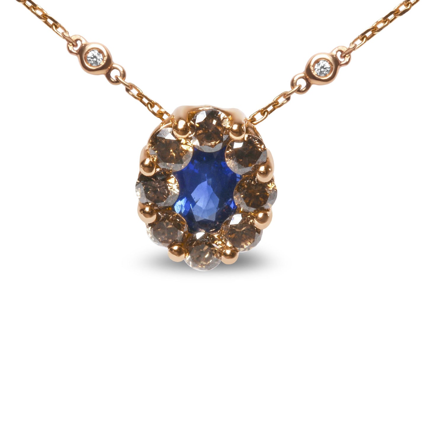 Front view of a rose metal necklace with an oval blue gemstone surrounded by round brown gemstones, and accented by two round white gemstones on the chain.