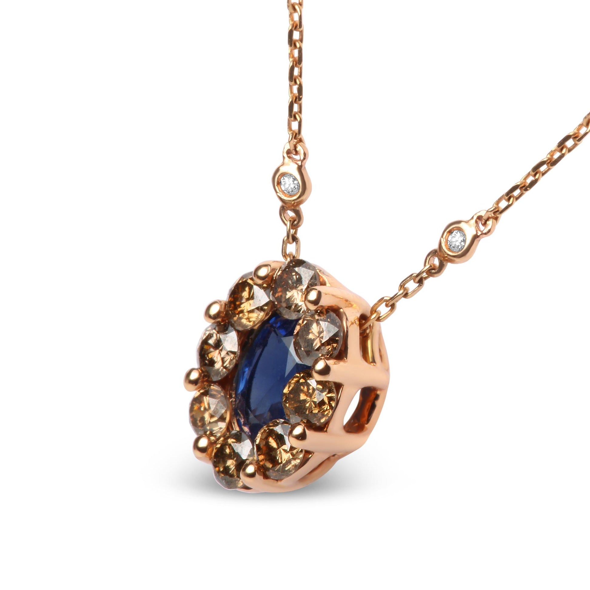Close-up angled view of a rose metal necklace pendant featuring an oval blue gemstone bezel set in the center, surrounded by round prong-set brown gemstones, with two round white gemstones bezel set along the chain.