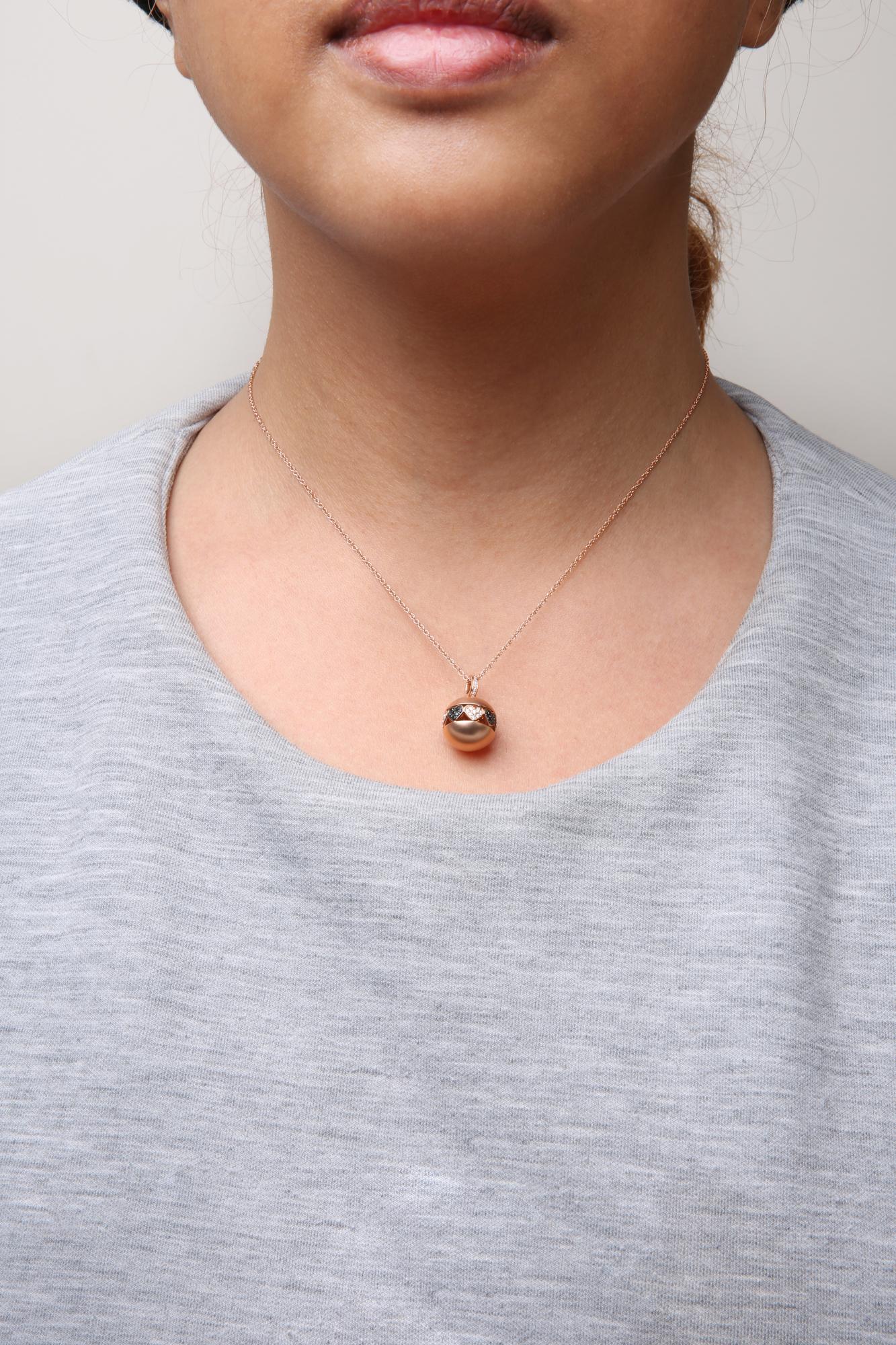 Close-up front view of a rose metal necklace on a model, featuring a circular pendant set with round white and black gemstones.