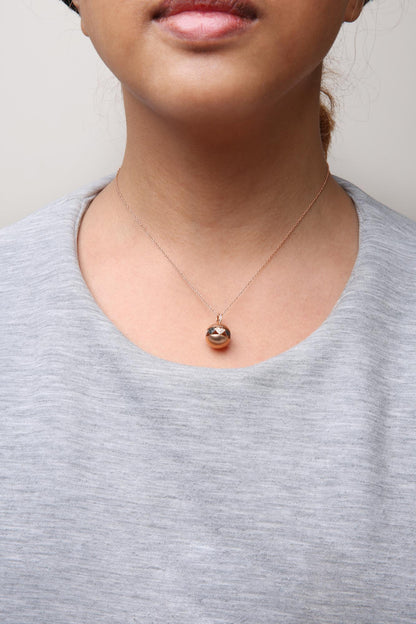 Close-up front view of a rose metal necklace on a model, featuring a circular pendant set with round white and black gemstones.