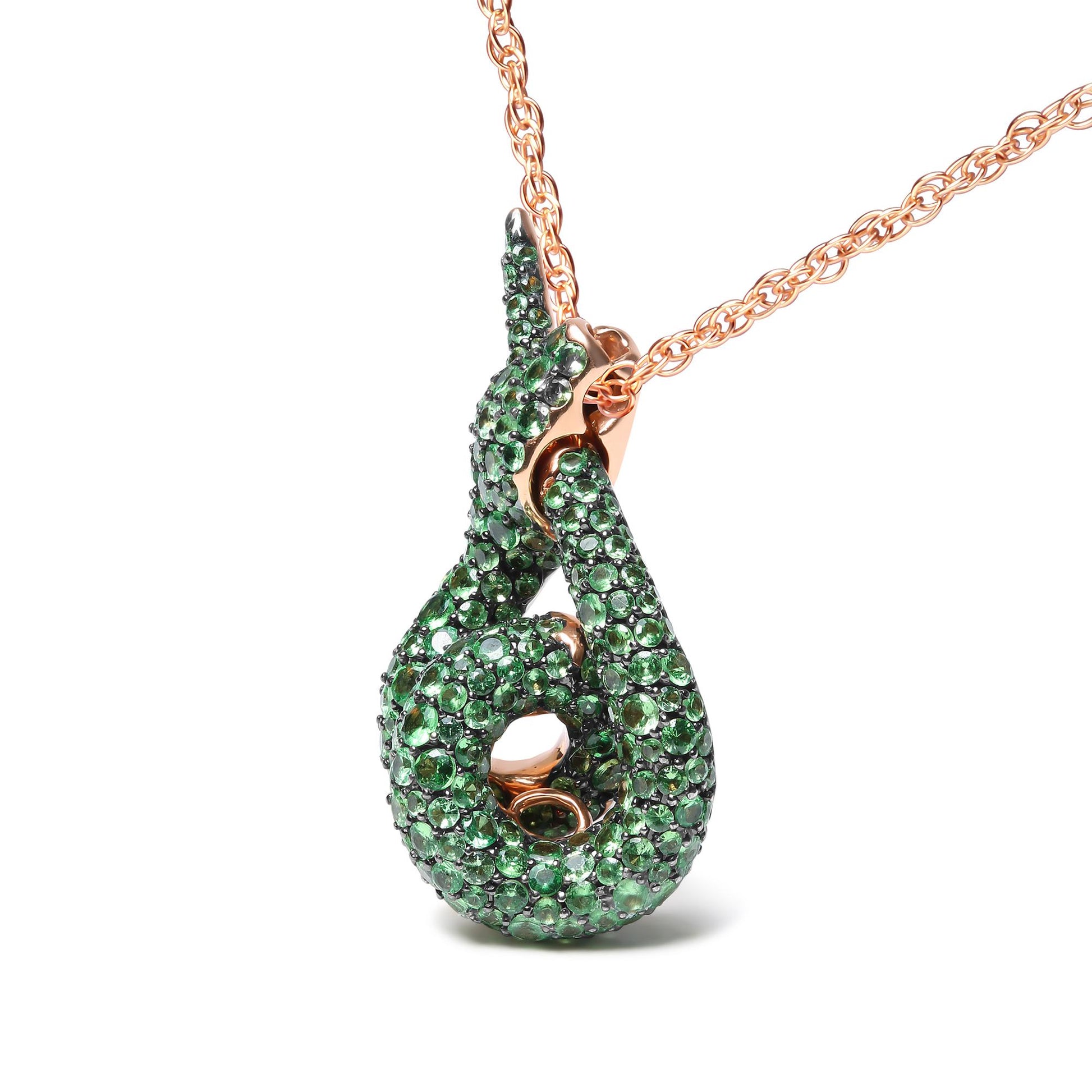 Rose metal necklace with a green gemstone pave setting pendant in an abstract swirl shape, shown in a close-up angled front view.