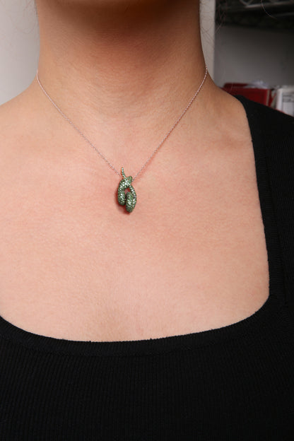 Close-up front view of a model wearing a rose metal necklace with a pendant featuring green round gemstones in a pave setting.