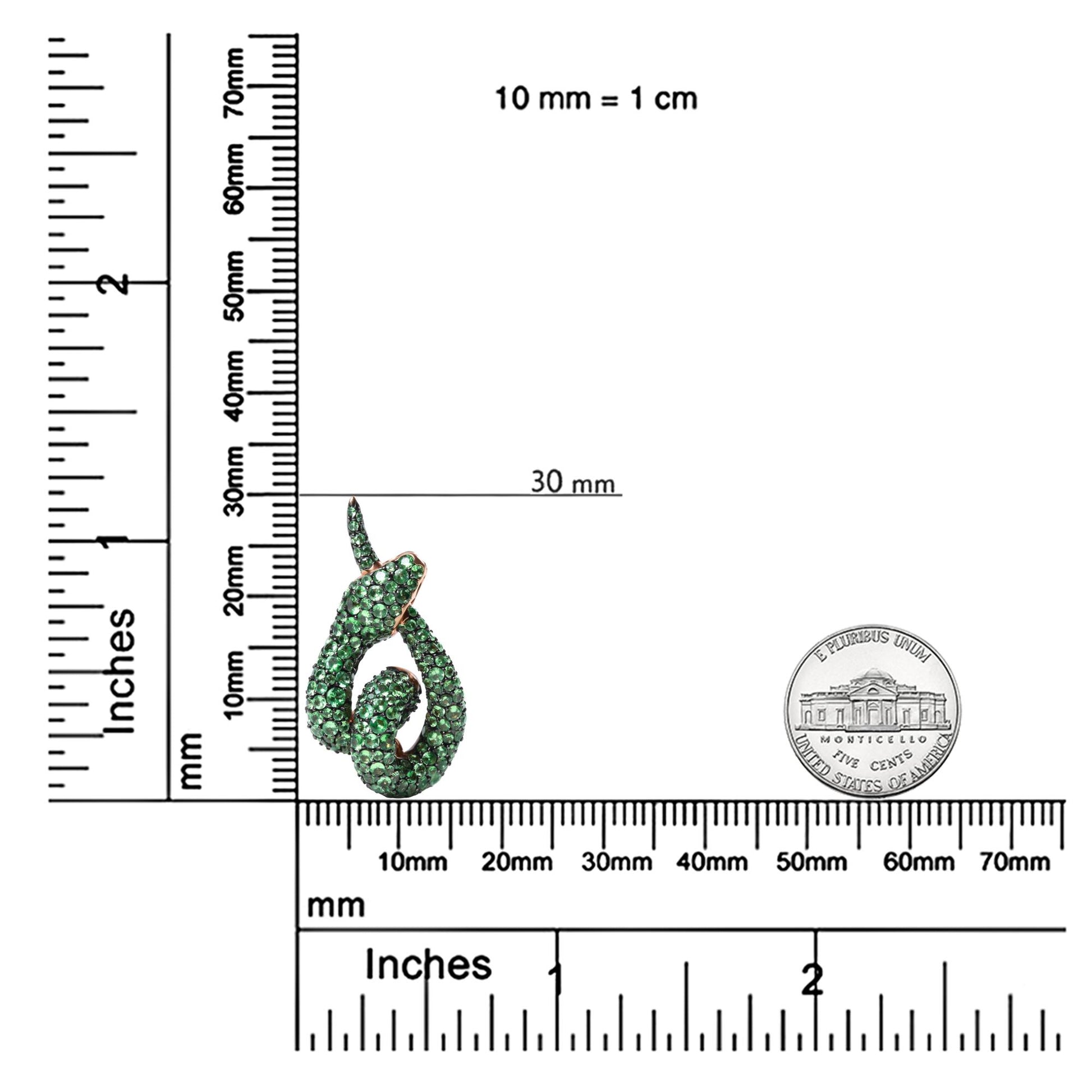 Rose metal necklace pendant with green round gemstones in pave setting, photographed on a ruler and scale for size reference at a slight front angle.