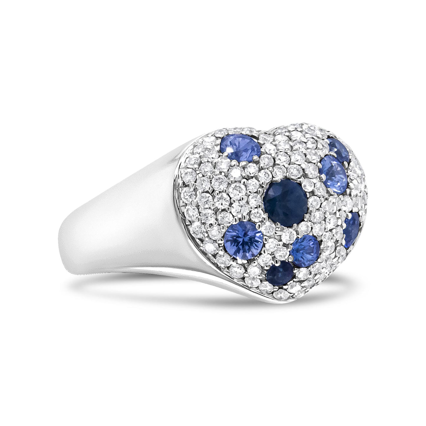Close-up side angle of a white metal ring with a heart-shaped top featuring a clustered pave setting of round white gemstones and scattered round blue gemstones.