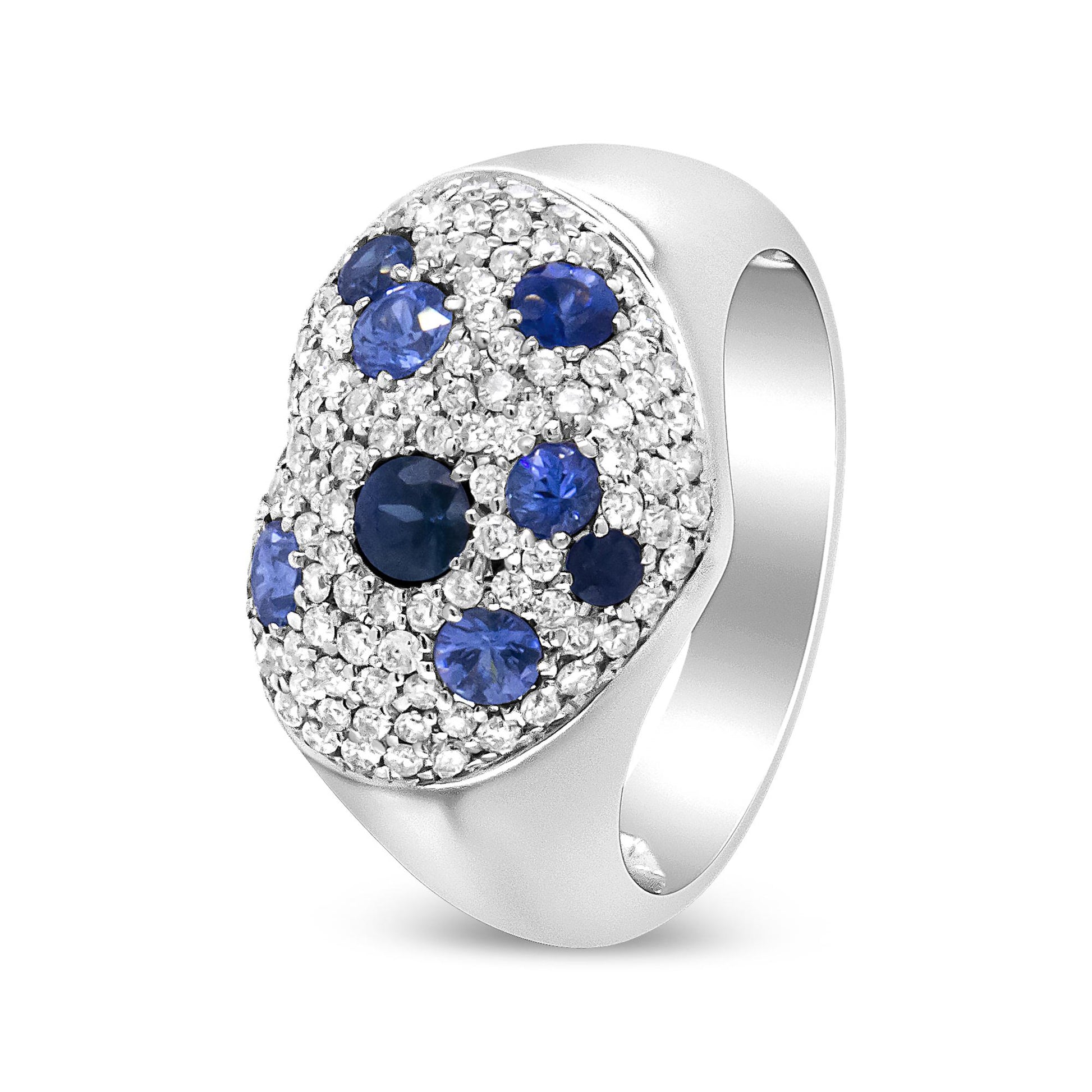 White metal ring with multiple round blue gemstones and numerous round white gemstones in prong and pave settings, shown angled from the front side.