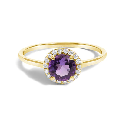 Close-up front angle of a yellow metal ring set with a round purple gemstone in the center, surrounded by small round white gemstones in a shared prong setting.