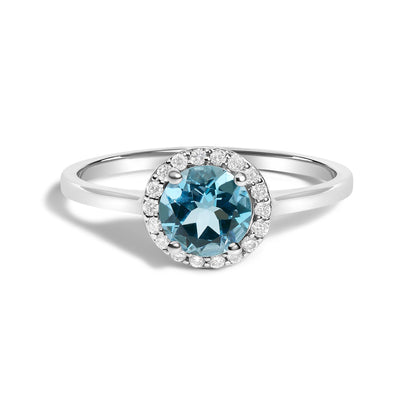Close-up front angle view of a white metal ring with a round blue gemstone center surrounded by multiple small round white gemstones in shared prong settings.