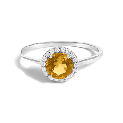 White metal ring shown from a slightly angled top view, featuring a round orange gemstone in the center with a surrounding halo of small round white gemstones in shared prong settings.
