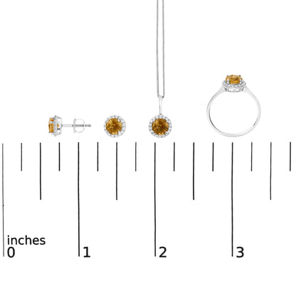 Jewelry set with round orange gemstones surrounded by white gemstones in a white metal setting, including stud earrings, a pendant necklace, and a ring, shown on a scale.