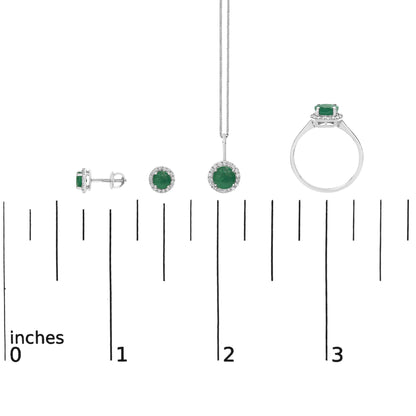 Set of white metal jewelry shown on a scale, including a pair of stud earrings, a pendant necklace, and a ring, each featuring a round green gemstone surrounded by small white gemstones, displayed in a front and side view with a white background.